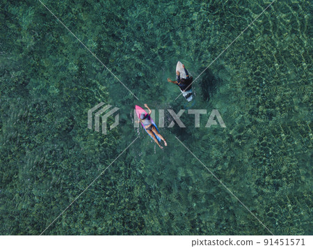 Couple surfers swimming in tropical water Couple surfers swimming in tropical water 91451571