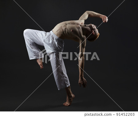 red-haired male dancer demonstrates the choreographic elements of the dance. photo shoot in the studio on a dark background red-haired male dancer demonstrates the choreographic elements of the dance. photo shoot in the studio on a dark background 91452203