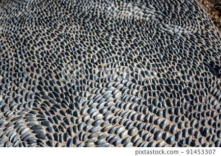 Selective focus on decorative pattern of river rocks laid in garden footpath. Selective focus on decorative pattern of river rocks laid in garden footpath. 91453307