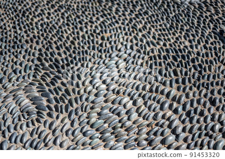 Selective focus on decorative pattern of river rocks laid in garden footpath.  91453320
