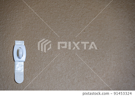 Selective focus on adhesive strip wall hanger that can be removed by pulling tape Selective focus on adhesive strip wall hanger that can be removed by pulling tape 91453324