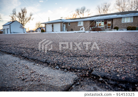 low angle selective focus on asphalt overlay paving on top of a concrete base of a residential street 91453325