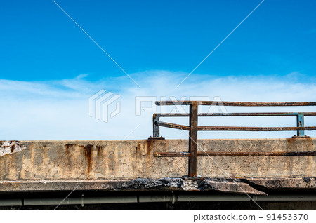 Damaged and bent guardrail along the edge of a bridge that needs repaired. Damaged and bent guardrail along the edge of a bridge that needs repaired. 91453370