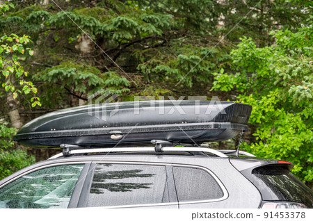 Roof rack and cargo box mounted on a vehicle with active precipitation. 91453378