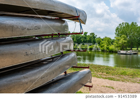 Aluminum canoes stacked on a trailer with a beach front and open water in the background Aluminum canoes stacked on a trailer with a beach front and open water in the background 91453389