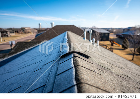 Contrast of frost line on a shingle roof as the sun rises and melts it 91453471