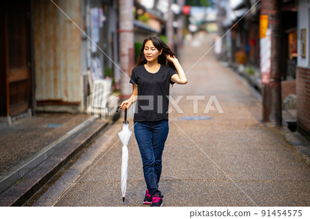 A woman taking a walk in the city after the rain 91454575