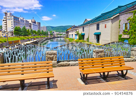 A view of the warehouses and benches of the Otaru Canal in the clear sky seen from the fresh green Hokkaido Otaru City, Asakusa Bridge Town Park 91454876