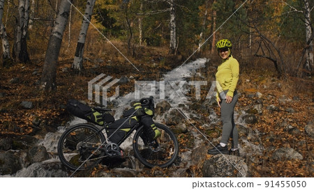 The woman travel on mixed terrain cycle touring with bikepacking. The traveler journey with bicycle bags. Sport tourism bikepacking. The woman travel on mixed terrain cycle touring with bikepacking. The traveler journey with bicycle bags. Sport tourism bikepacking. 91455050