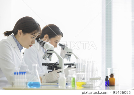 一個穿白大褂的女人透過顯微鏡看 一個穿白大褂的女人透過顯微鏡看 91456095