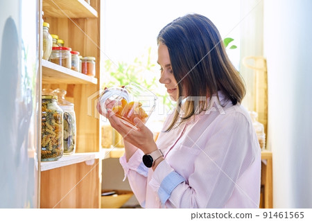 Young woman in kitchen with containers jars of food, with dried apricots 91461565
