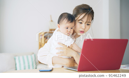 一個抱著孩子在家工作的女人，一個在撫養孩子的同時在家工作的女人 91462249
