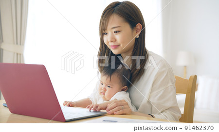 一個抱著孩子在家工作的女人，一個在撫養孩子的同時在家工作的女人 91462370