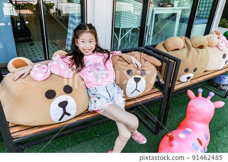 Closeup Asia little girl pose with bear on chair Closeup Asia little girl pose with bear on chair 91462485