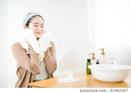 A woman who wipes her face with a towel after washing her face A woman who wipes her face with a towel after washing her face 91462867
