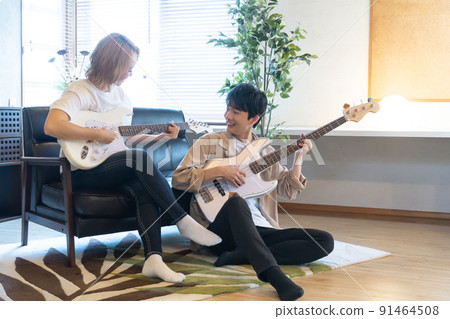 Young men and women playing guitar and bass in the living room 91464508