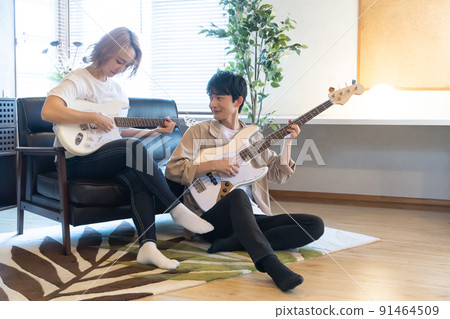 Young men and women playing guitar and bass in the living room 91464509