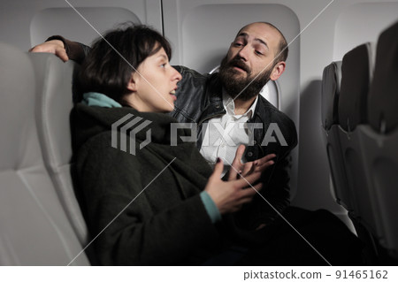 Jet passengers having conversation on commercial flight, travelling by plane to go on holiday journey destination. Couple flying abroad with airplane transport to arrive on vacation. 91465162