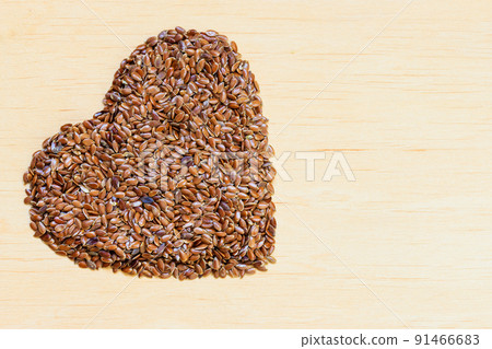 Raw flax seeds linseed heart shaped on wooden table Raw flax seeds linseed heart shaped on wooden table 91466683