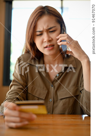 Angry Asian woman talking with the bank's call-centre service to complain problems. Angry Asian woman talking with the bank's call-centre service to complain problems. 91467070