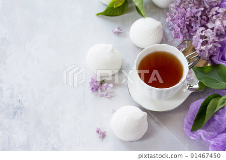 Delicate vanilla marshmallow on a white delicate plate. Still life with marshmallows, a cup of tea and lilac lilac against a vintage stone background. Copy space. Delicate vanilla marshmallow on a white delicate plate. Still life with marshmallows, a cup of tea and lilac lilac against a vintage stone background. Copy space. 91467450