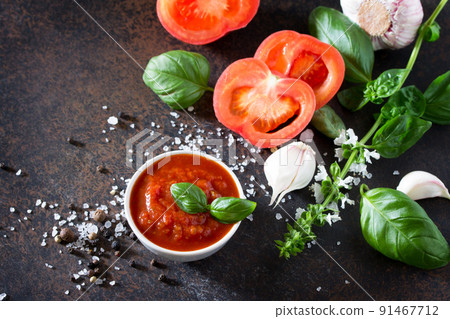 Tomato ketchup sauce in a bowl with spices, basil leaves and tomatoes on the kitchen table. Tomato ketchup sauce in a bowl with spices, basil leaves and tomatoes on the kitchen table. 91467712