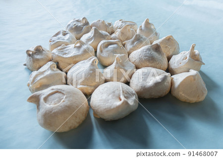 Homemade french milk-colored meringues on blue paper 91468007