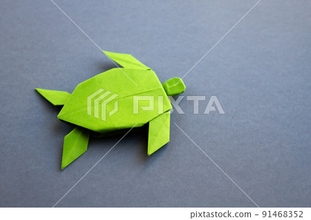 Green paper turtle origami isolated on a grey background Green paper turtle origami isolated on a grey background 91468352