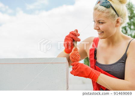 Woman using string as level in wall construction. Woman using string as level in wall construction. 91469069