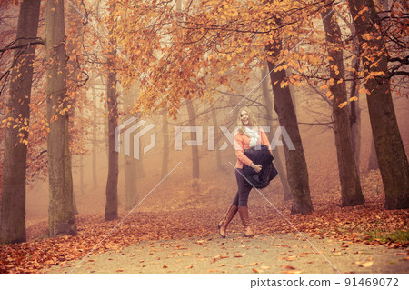 Smiling fashion blonde woman with jacket in park. 91469072