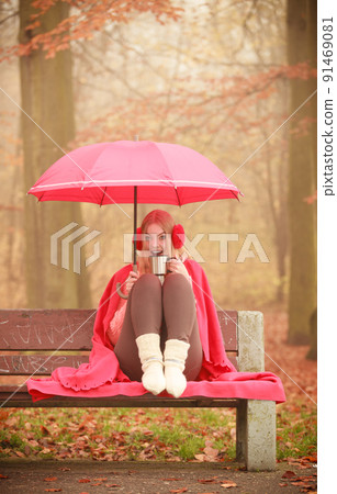 Girl in autumn park enjoying hot drink Girl in autumn park enjoying hot drink 91469081