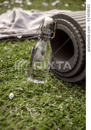 Yoga Mat with a glass eco reusable bottle of water, outdoor exercising. Healthy lifestyle Yoga Mat with a glass eco reusable bottle of water, outdoor exercising. Healthy lifestyle 91469683