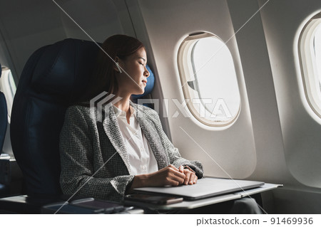 Tired business asian lady napping on seat while traveling by airplane. Commercial transportation by planes. 91469936