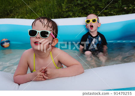 Wet serious children in the pool in sunglasses. Summer is a time of pleasure and fun 91470255