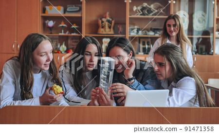 Schoolgirls friends working together in class with a laptop and eating apples. Schoolgirls friends working together in class with a laptop and eating apples. 91471358