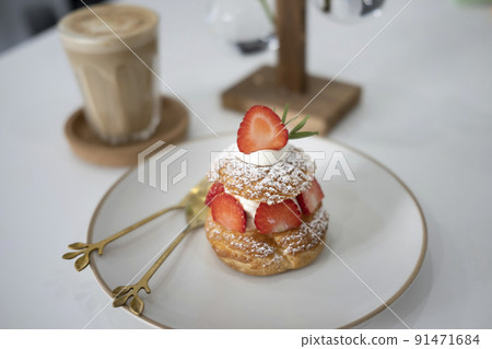 Fresh choux cream puff with whipped cream and strawberries on white plate. 91471684