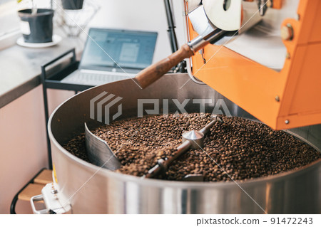 Close up of coffee roasting machine with coffee beans in small coffee manufacturing Close up of coffee roasting machine with coffee beans in small coffee manufacturing 91472243