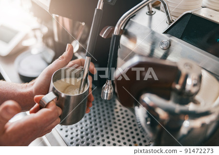 Professional barista warming milk In metal jug with steam of coffee machine Professional barista warming milk In metal jug with steam of coffee machine 91472273