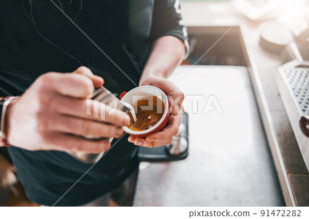 Professional Barista pouring milk in cup of fresh made coffee for making latte or cappuccino 91472282