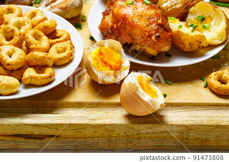tasty and healthy food, lunch in rural style - fried chicken meat and unpeeled potatoes, eggs, green leek, salt and garlic, cooked food on a wooden kitchen board tasty and healthy food, lunch in rural style - fried chicken meat and unpeeled potatoes, eggs, green leek, salt and garlic, cooked food on a wooden kitchen board 91473808