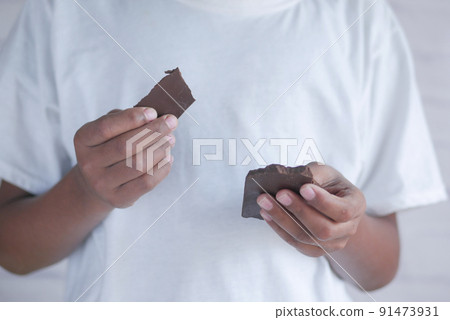 young man eating dark chocolate close up young man eating dark chocolate close up 91473931
