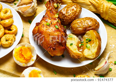 tasty and healthy food, lunch in rural style - fried chicken meat and unpeeled potatoes, eggs, green leek, salt and garlic, cooked food on a wooden kitchen board tasty and healthy food, lunch in rural style - fried chicken meat and unpeeled potatoes, eggs, green leek, salt and garlic, cooked food on a wooden kitchen board 91474377
