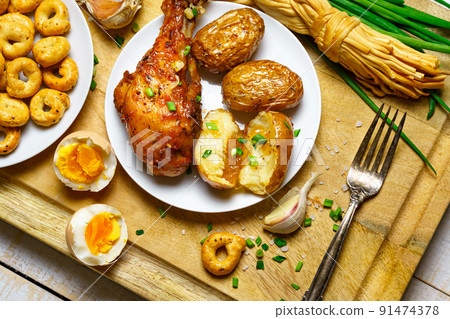 tasty and healthy food, lunch in rural style - fried chicken meat and unpeeled potatoes, eggs, green leek, salt and garlic, cooked food on a wooden kitchen board tasty and healthy food, lunch in rural style - fried chicken meat and unpeeled potatoes, eggs, green leek, salt and garlic, cooked food on a wooden kitchen board 91474378