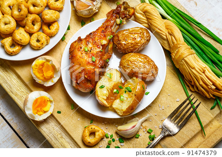tasty and healthy food, lunch in rural style - fried chicken meat and unpeeled potatoes, eggs, green leek, salt and garlic, cooked food on a wooden kitchen board tasty and healthy food, lunch in rural style - fried chicken meat and unpeeled potatoes, eggs, green leek, salt and garlic, cooked food on a wooden kitchen board 91474379