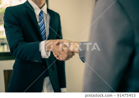 The businessmen shake hands after the meeting was successful and agreed upon The businessmen shake hands after the meeting was successful and agreed upon 91475453