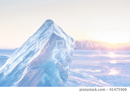 Winter landscape with ice hummocks glittering in the sun and mountains of Lake Baikal in Siberia at sunset. Natural background. 91475906
