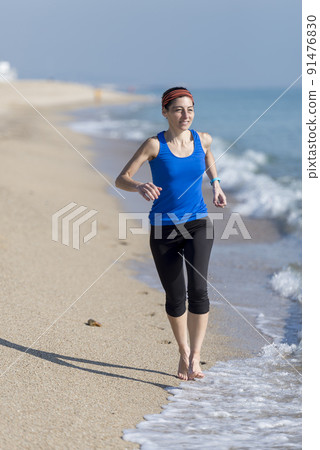 Front view of women jogging on beach close to water Front view of women jogging on beach close to water 91476830