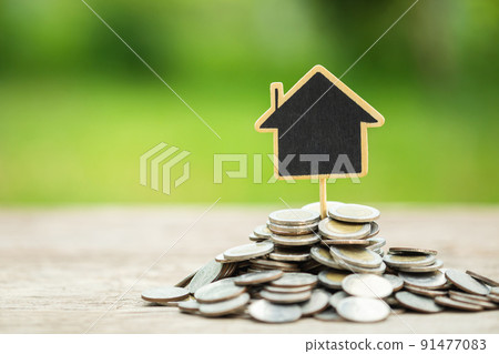 Wooden house model on the pile coin on wooden plank with nature space background. House investment concept 91477083
