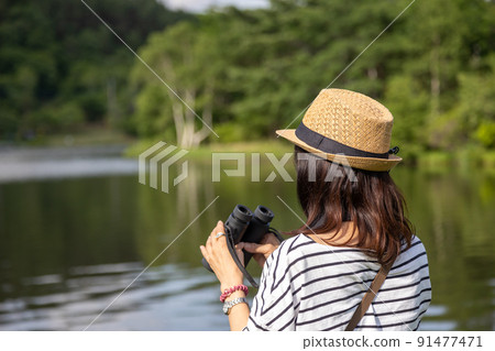 A woman bird watching on a lake in the plateau 91477471