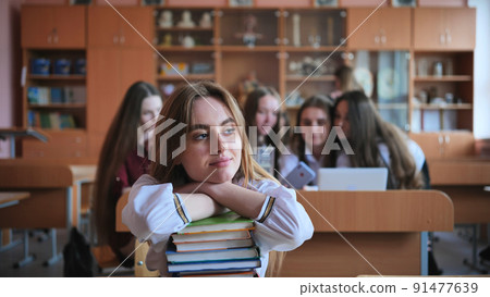 A student poses with textbooks at her desk in her class. A student poses with textbooks at her desk in her class. 91477639